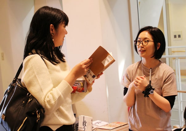 本を持った女性と話すスタッフ